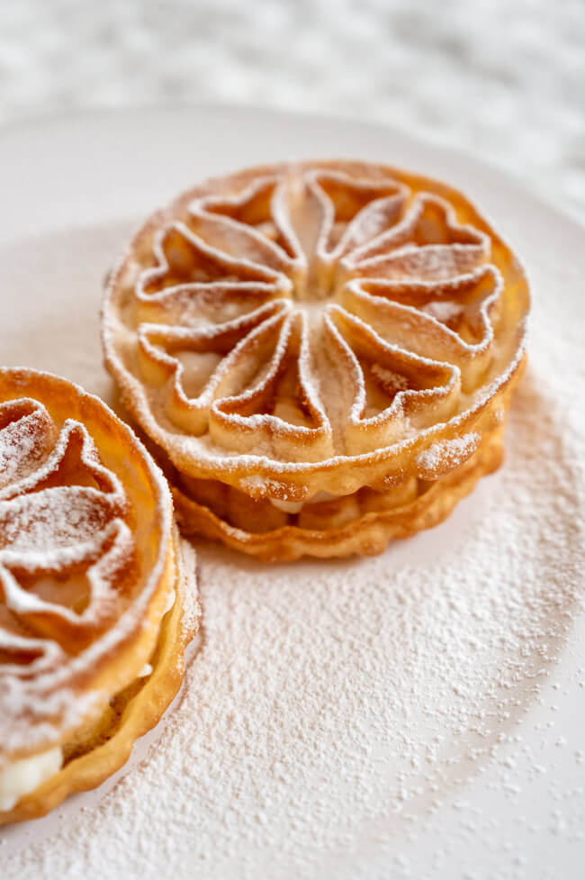 Baci Panteschi oder Tortelle auf weißem Porzellanteller angerichtet mit Puderzucker bestäubt