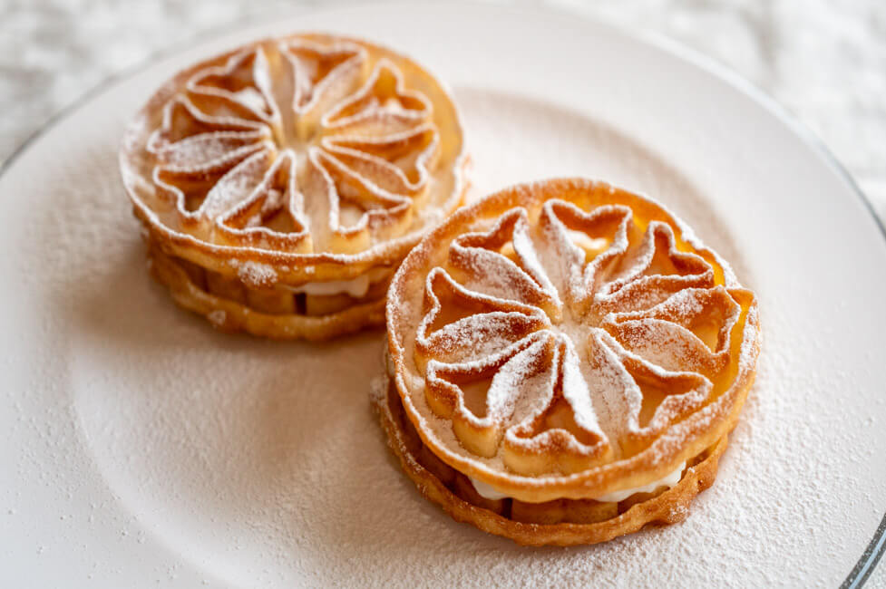 Baci Panteschi oder Tortelle auf weißem Porzellanteller angerichtet mit Puderzucker bestäubt