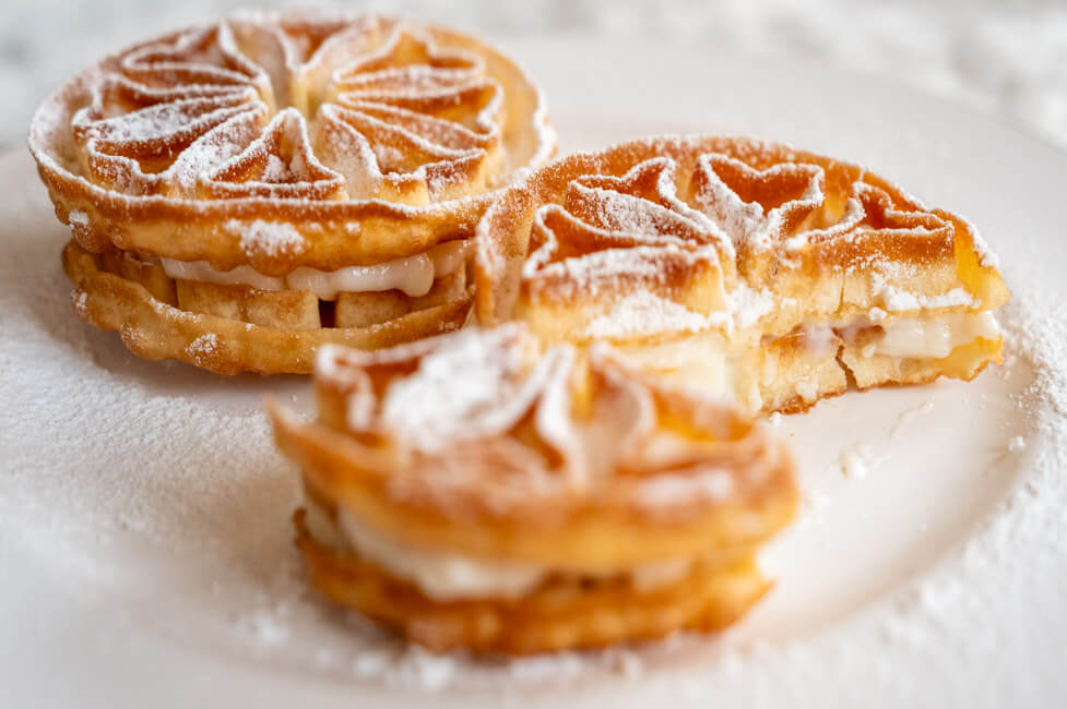 Baci Panteschi oder Tortelle auf weißem Porzellanteller angerichtet mit Puderzucker bestäubt