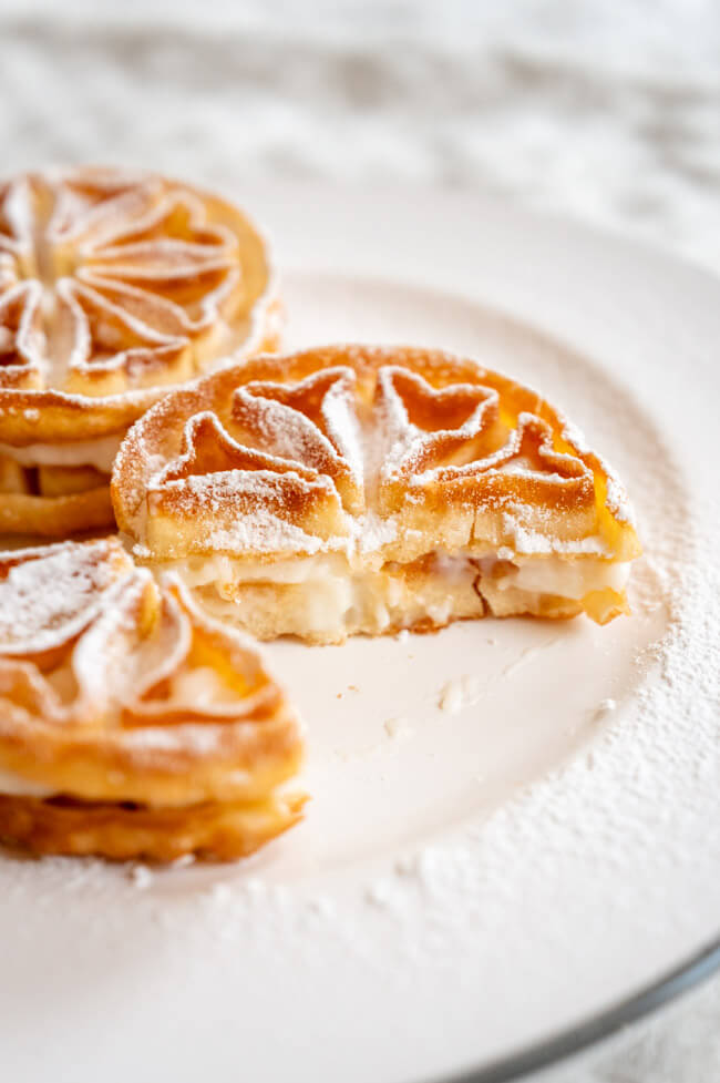 Baci Panteschi oder Tortelle auf weißem Porzellanteller angerichtet mit Puderzucker bestäubt
