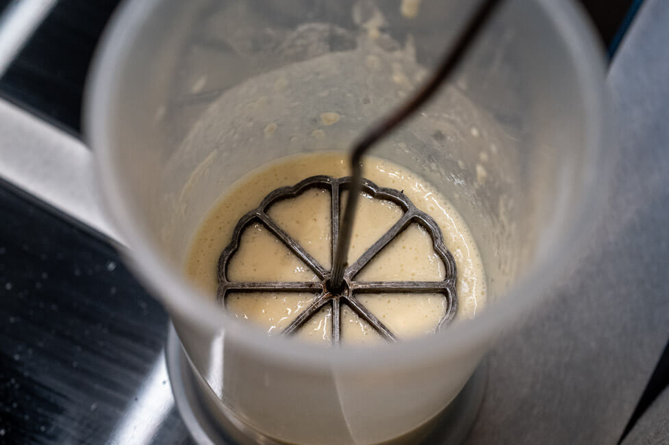 Rosettenwaffeleisen wird in Waffelteig getunkt