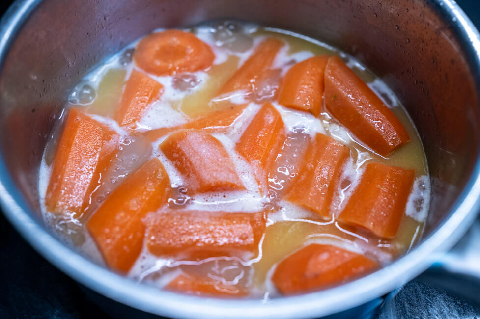 Karotten werden mit Brühe und Butter im Topf gekocht