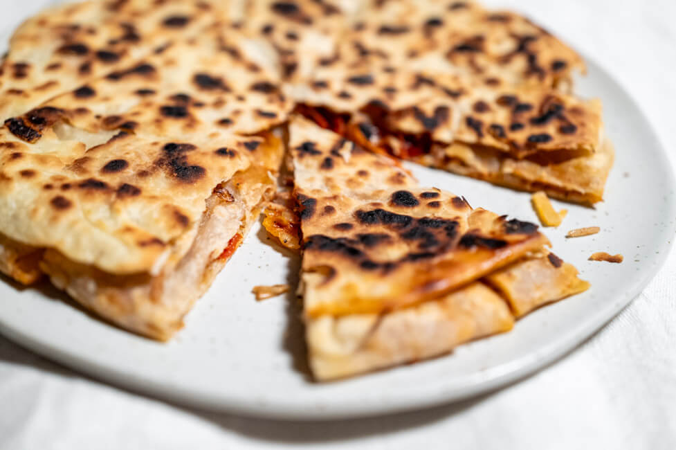 Byrek mit Zwiebeln und Tomate auf schwarzem Teller