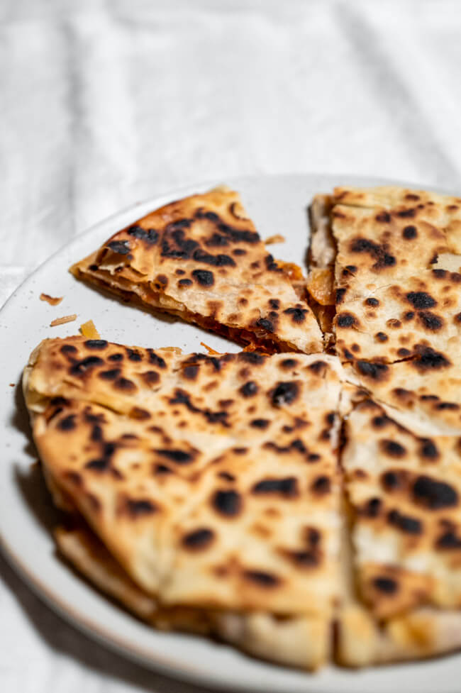 Byrek mit Zwiebeln und Tomate auf schwarzem Teller