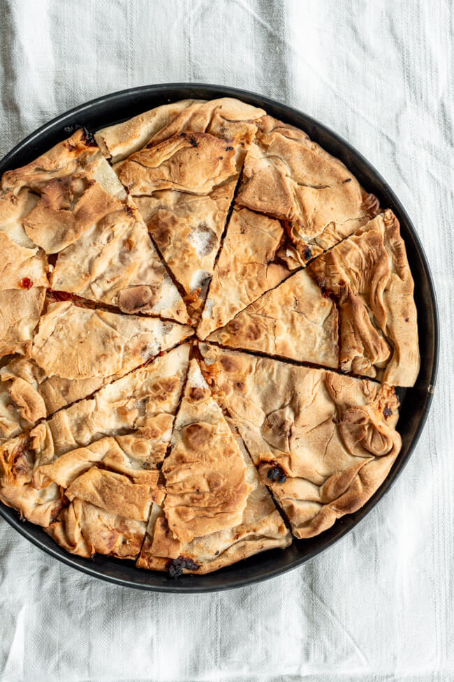 Byrek mit Zwiebeln und Tomate auf schwarzem Teller
