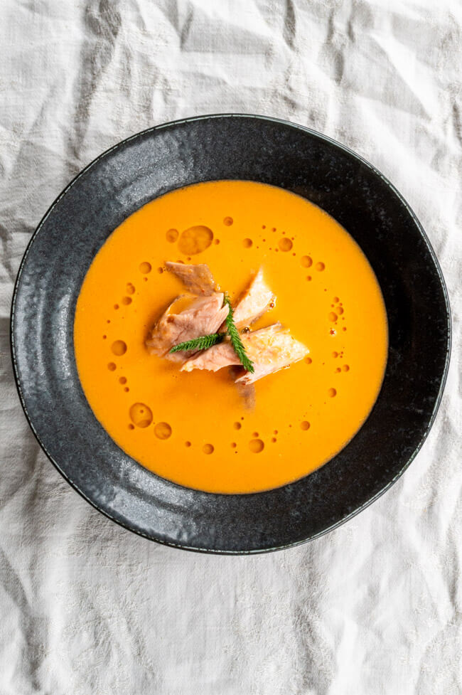 Tomatensuppe mit geräuchertem Fisch in schwarzem Teller