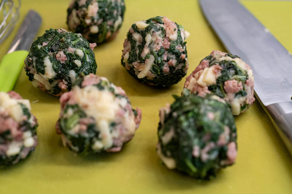 Von Hand geforme Polpette auf grünem Schneidebrett