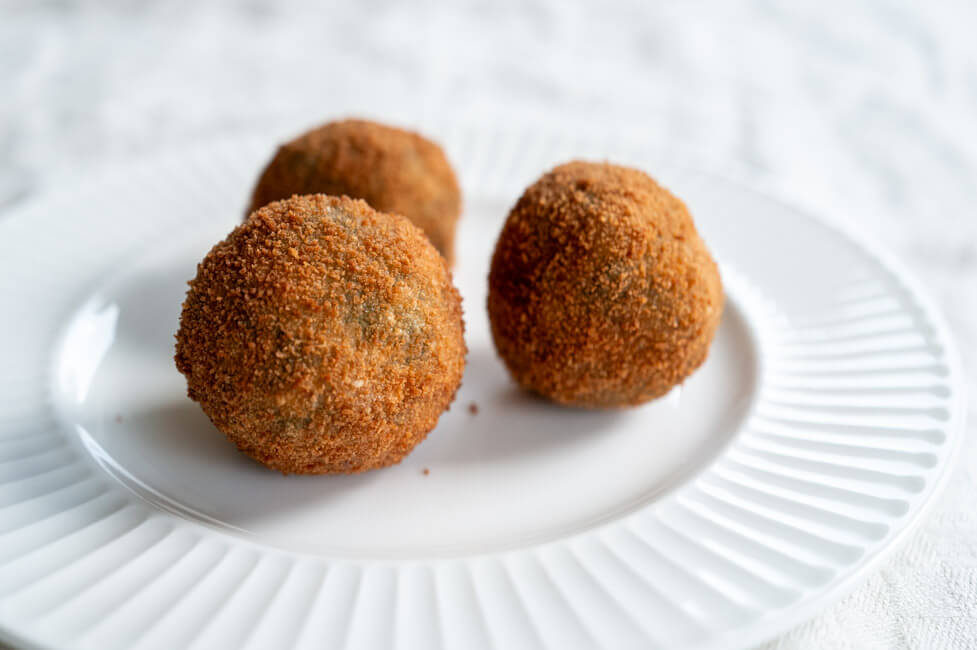 3 Polpette mit wildem Brokkoli auf weißem Teller