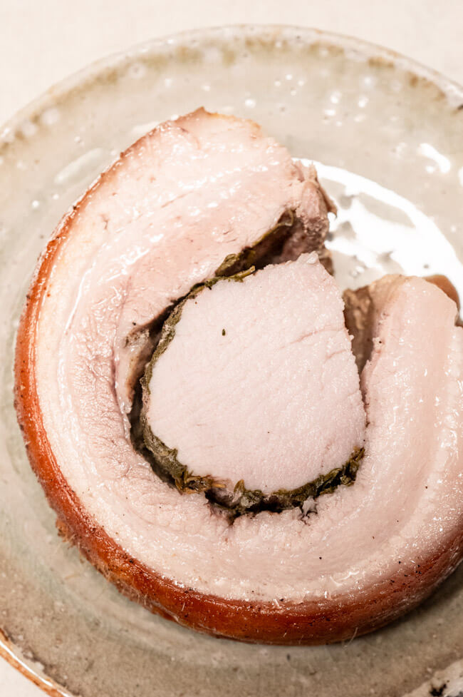 Eine Scheibe Porchetta auf Keramikteller