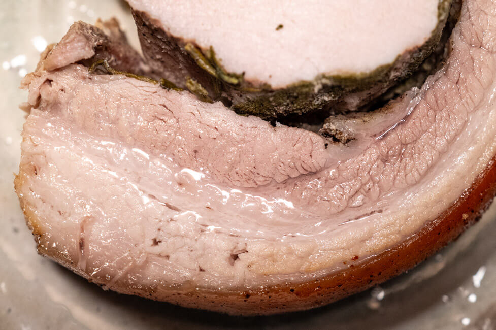 Eine Scheibe Porchetta auf Keramikteller