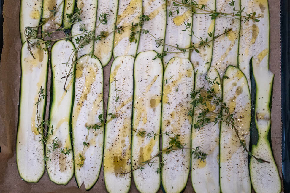 Zucchinischeiben mit Olivenöl, Thymian, Salz und Pfeffer auf Backblech ausgebreitet.