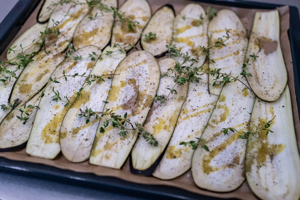 Auberginenscheiben mit Olivenöl, Thymian, Salz und Pfeffer auf Backblech ausgebreitet.
