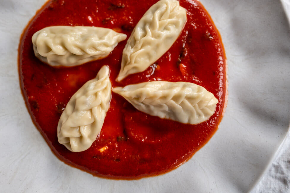 4 Culurgiones mit Tomatensauce auf hellem Teller angerichtet