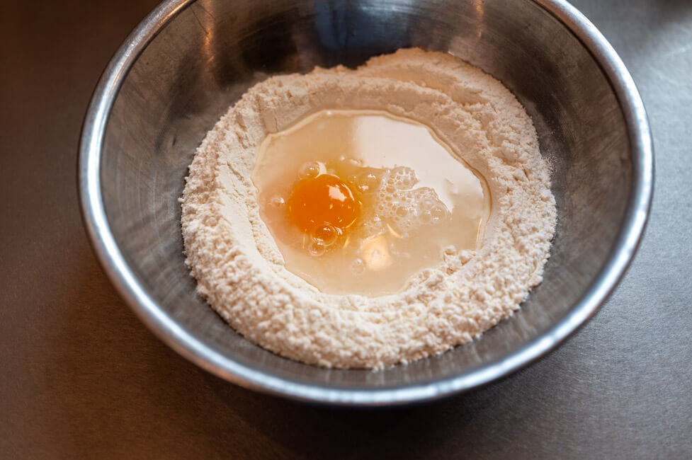 Schüssel mit Mehl, Ei und Wasser für den Pastateig