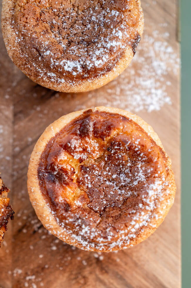 Pasteis de Nata auf Holzbrett und grünem Untergrund