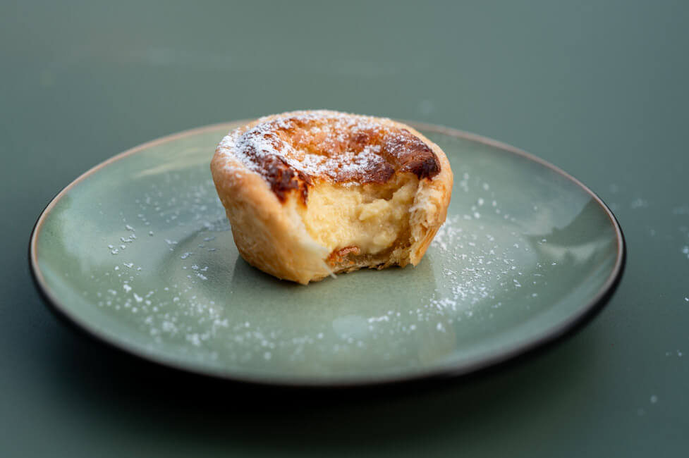 Pasteis de Nata auf grünem Teller und grünem Untergrund