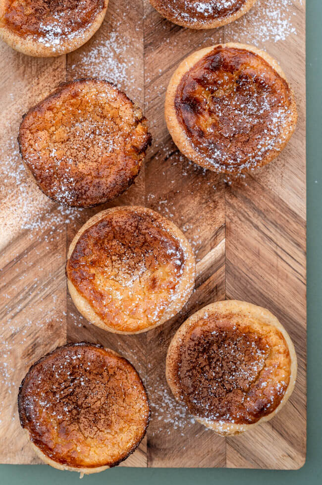 Pasteis de Nata auf Holzbrett und grünem Untergrund