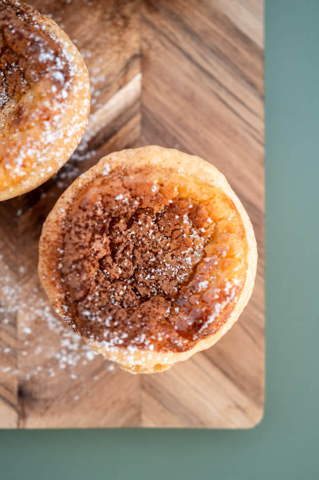 Pasteis de Nata auf Holzbrett und grünem Untergrund