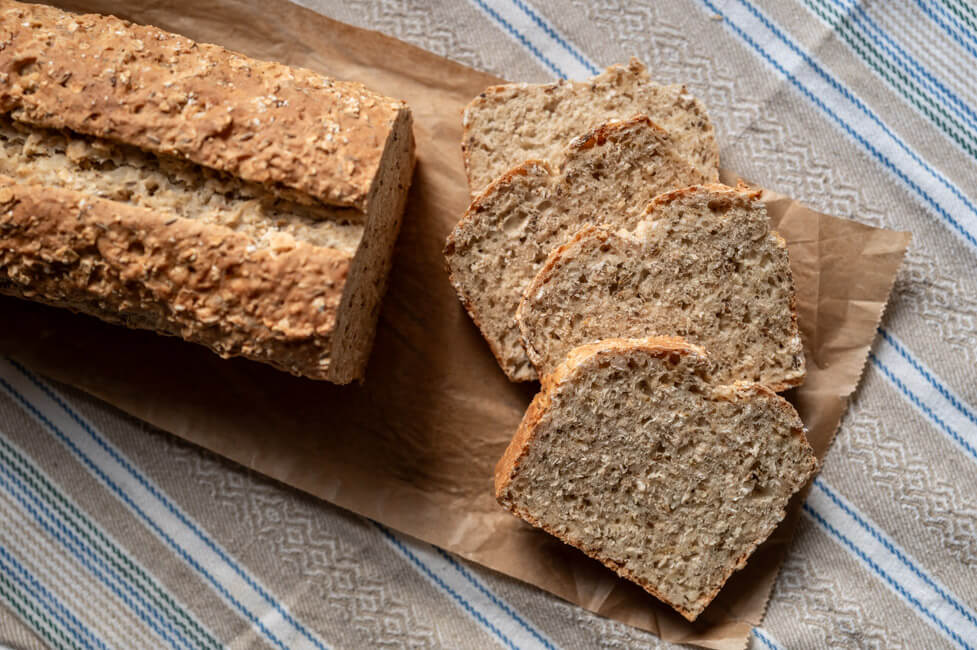 Isländisches Kümmelbrot aufgeschnitten auf Backpapier und gemustertem Tuch