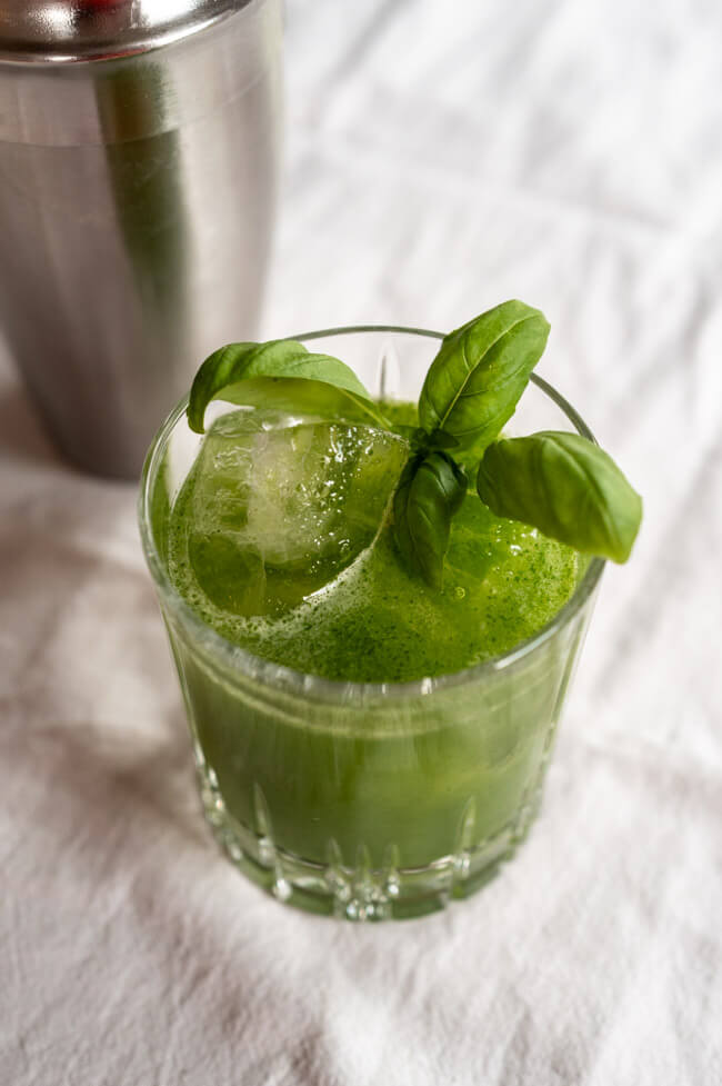 Gin Basil Smash angerichtet in Tumbler mit Eis und Baislikumblatt