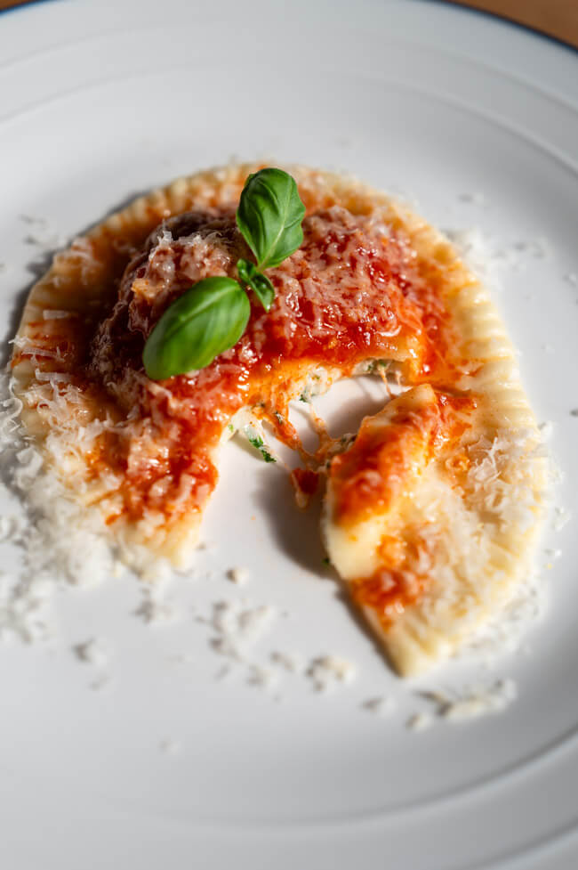 Weißer Teller mit angeschnittenem Ravioli