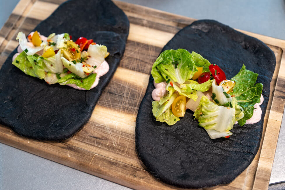 Pita mit Creme Tarama und Salat mit Vinaigrette auf Holzbrett