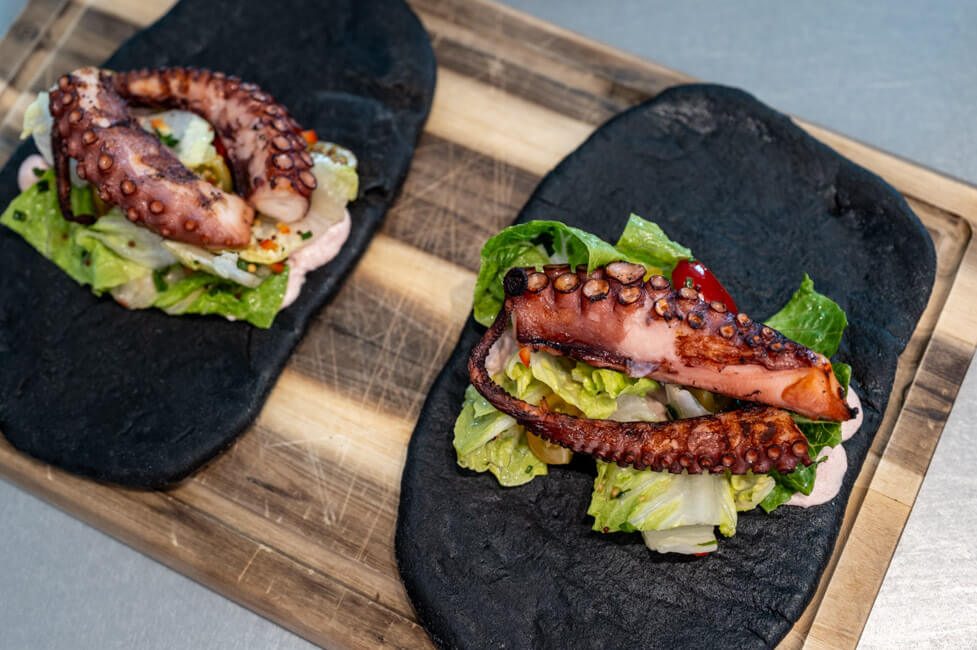Pita mit Creme Tarama und Salat mit Vinaigrette und gegrilltem Oktopus auf Holzbrett