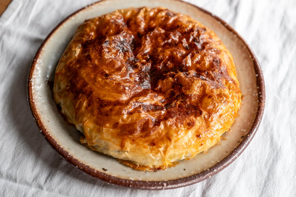 Fertig gebackene Pastilla auf Keramikteller und weißer Tischdecke