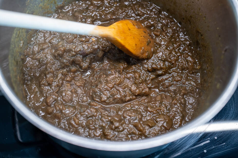 Eingedickter Zwiebelsud im Topf mit Kochlöffel