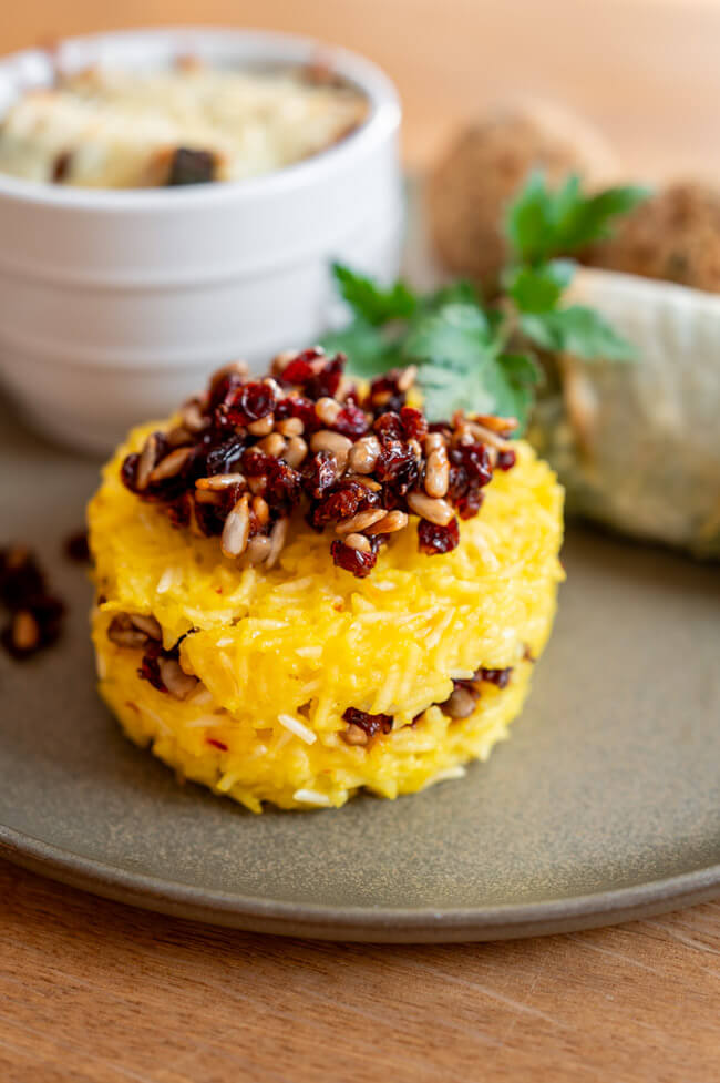Tahchin mit Berberitzen-Sonnenblumenkern-Topping mit den anderen Mezze auf grünem Porzellanteller