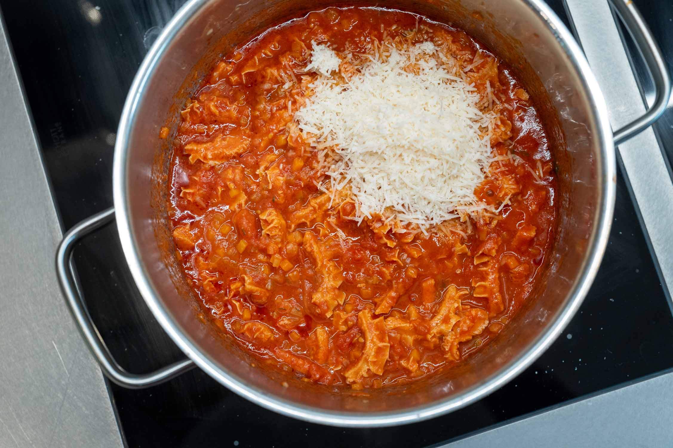 Fertig geschmorte Kutteln in Tomatensoße mit Parmesan im Kochtopf
