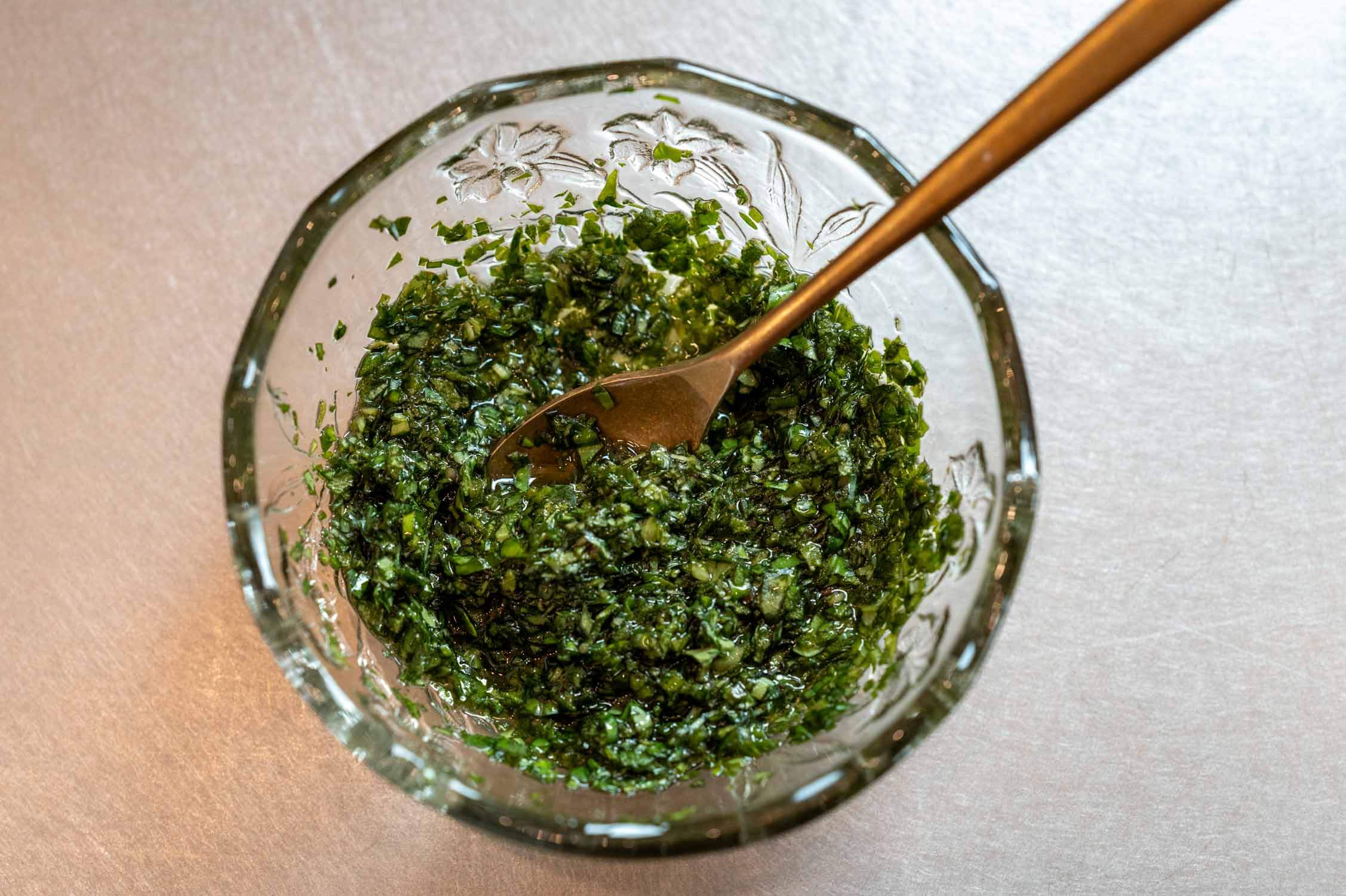 Kräuteröl in Glasschüssel mit goldenem Löffel