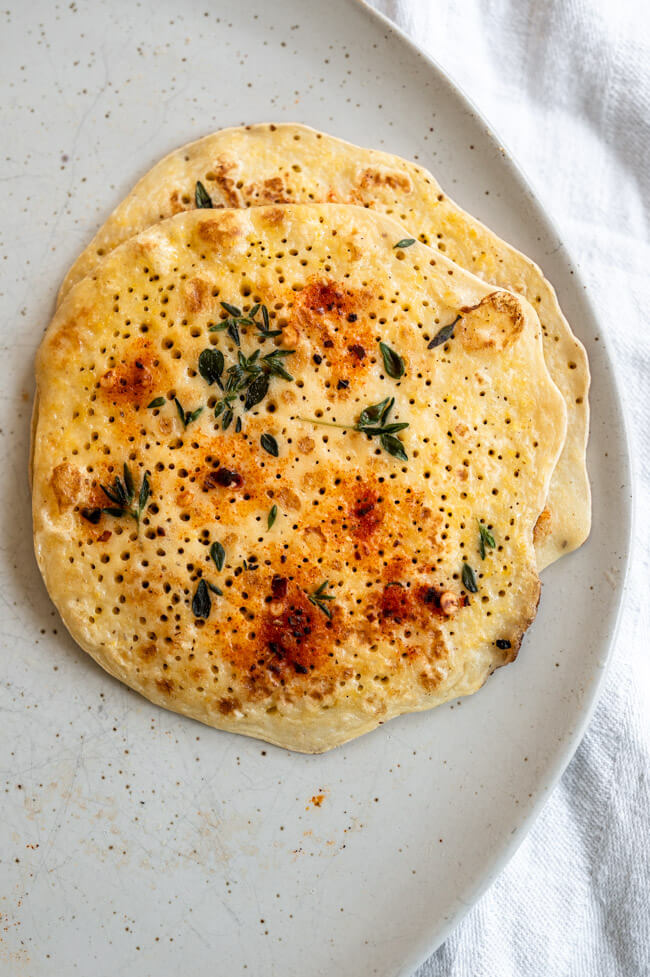 Polenta Pfannkuchen auf hellem Keramikteller und weißem Tischtuch