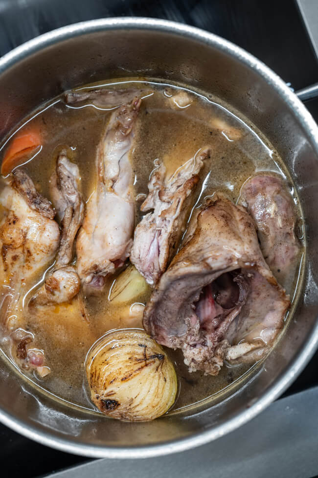 Kaninchenfleisch wird in Topf mit Brühe gekocht