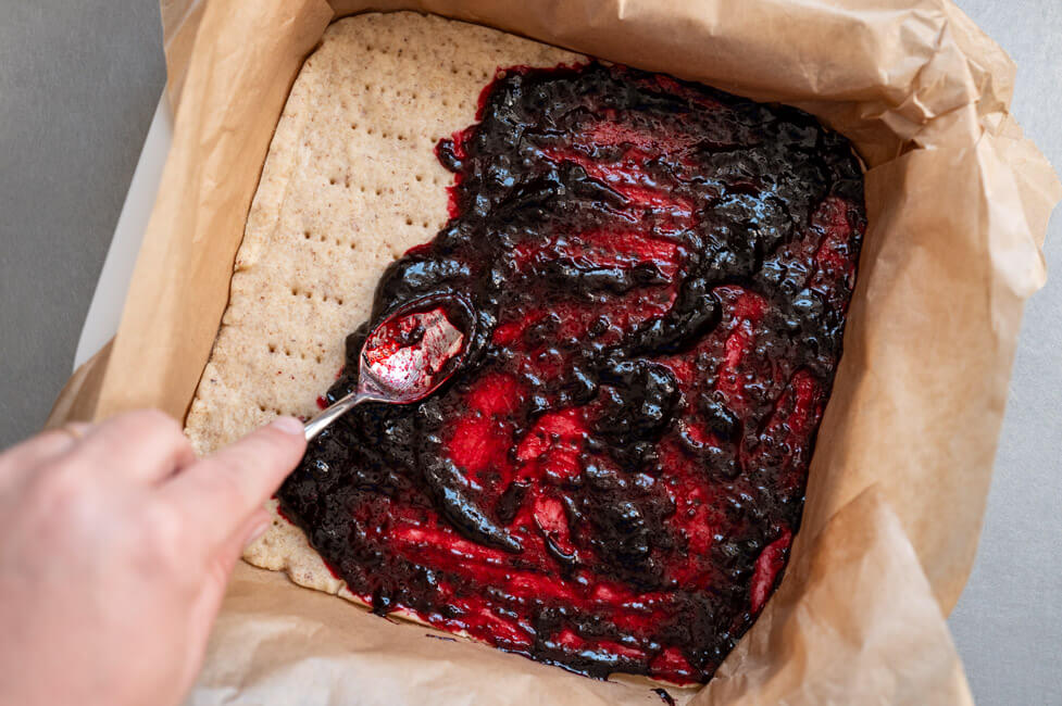 Haskap-Beeren Fruchtaufstrich wird auf Mürbeteigboden gestrichen
