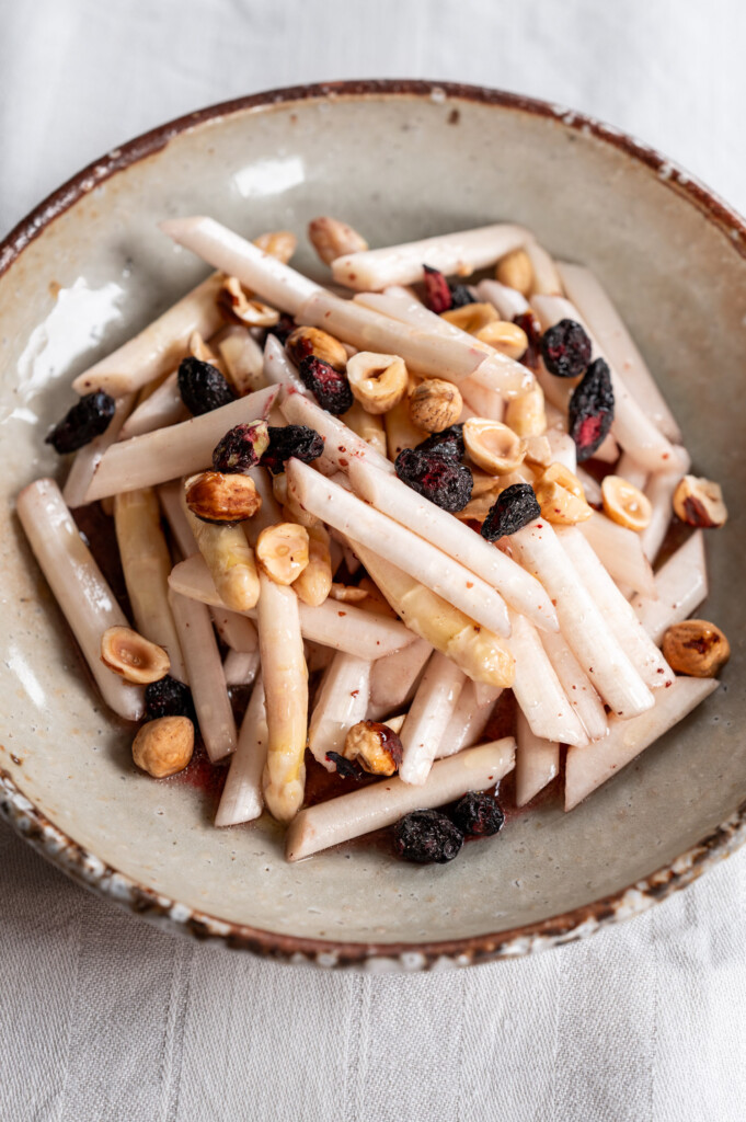 Spargelsalat mit Haselnüssen und Haskap-Beeren angerichtet auf Keramikteller.