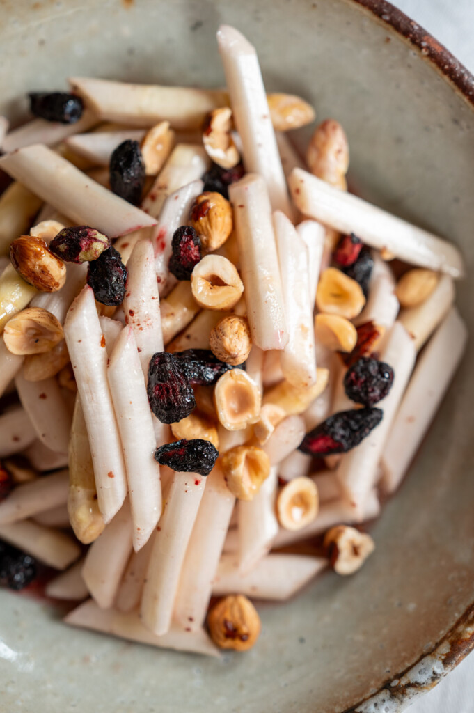 Spargelsalat mit Haselnüssen und Haskap-Beeren angerichtet auf Keramikteller.