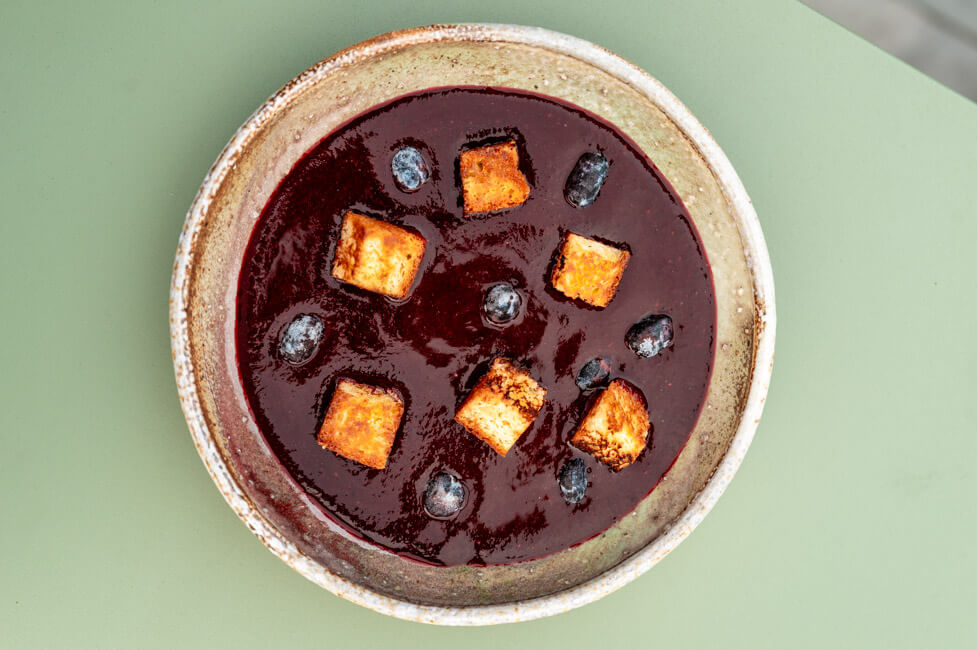 Haskap-Beeren Gazpacho mit Brioche auf grünem Untergrund