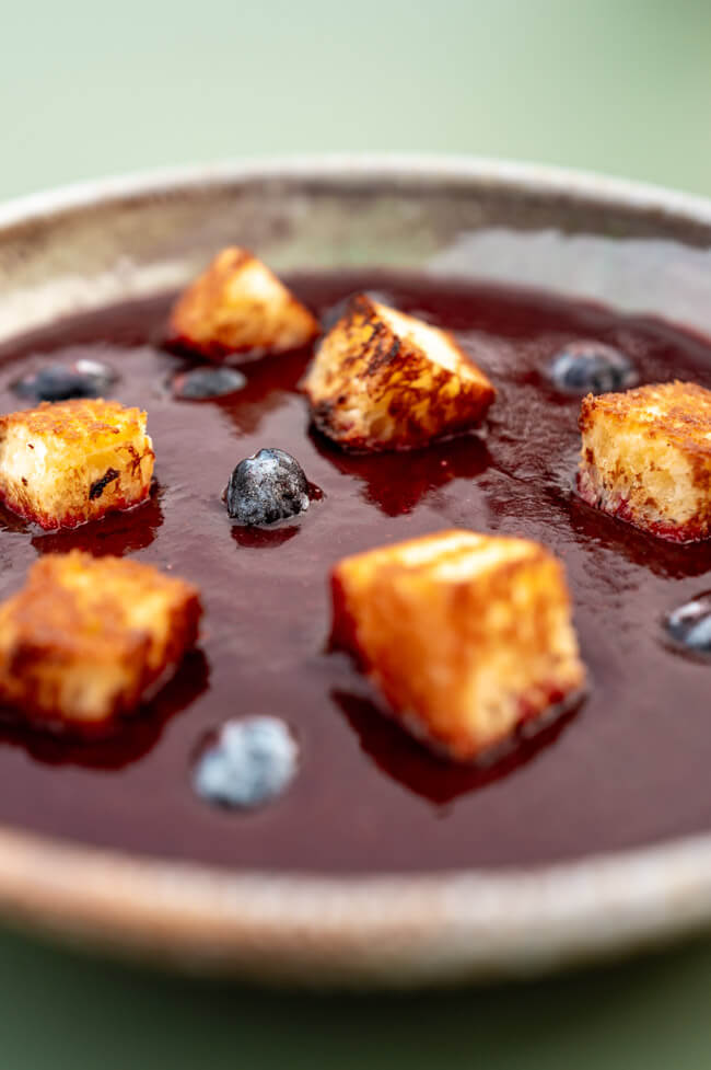 Haskap-Beeren Gazpacho mit Brioche auf grünem Untergrund
