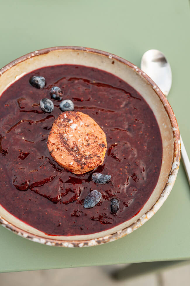 Haskap-Beeren Gazpacho mit gerösteter Foie Gras auf grünem Tisch