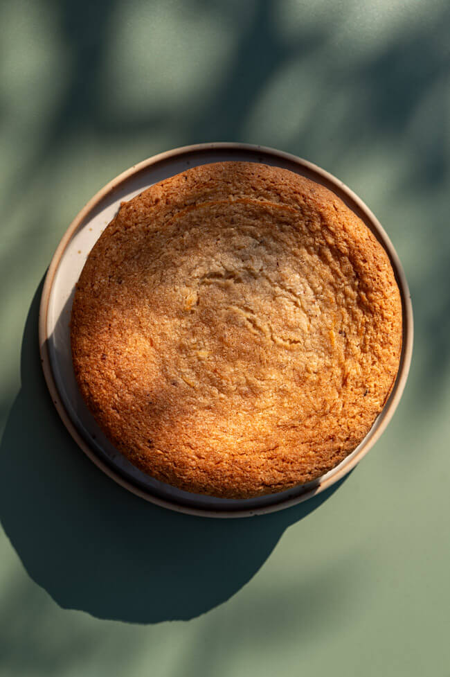Haselnuss-Käsekuchen mit Skyr auf Teller angerichtet auf grünem Tisch im Sonnenlicht