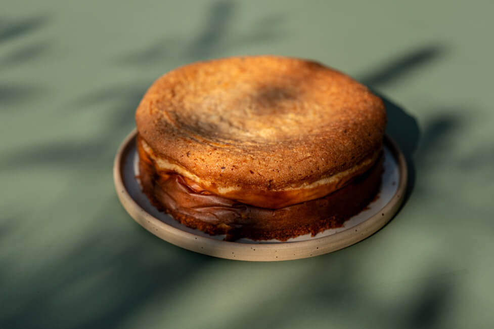 Haselnuss-Käsekuchen mit Skyr auf Teller angerichtet auf grünem Tisch im Sonnenlicht